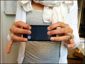 Een vrouw met lange slanke vingers en twee zilveren ringen demonstreert de braille-invoer op een zwarte iPhone 5.