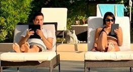 Man en vrouw die elk op een ligstoel in de zon een boek lezen op een e-reader