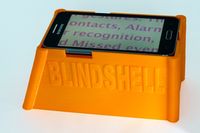 oranje plastic frame waarop een smartphone ligt, op de voorzijed staat het woord BlindShell