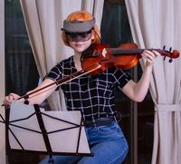  Foto van een jongedame die viool speelt en daarbij gebruik maakt van de Acesight om de muziekpartituur te lezen.